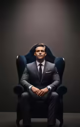 a man wearing a suit is sitting in a chair