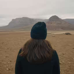 back of a person standing outside and mountains in the background