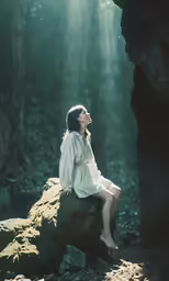 woman sitting on rock in wooded area with light coming in