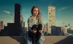 a woman sitting on top of a cement wall