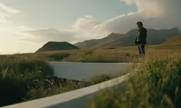 a person standing in a field next to some mountains