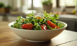 a bowl filled with lettuce and sliced tomatoes