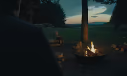 the man is setting up his campfire for a night time meal