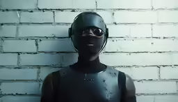 a man wearing a helmet and goggles in front of a wall