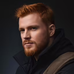 a man with red hair and beard in a black jacket