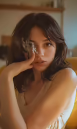a young lady with wavy dark hair is sitting down