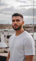 man in white tshirt standing by sailboats