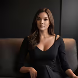 a woman sitting on a couch in a black dress