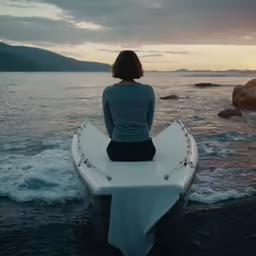 the girl sits on a boat at the shore