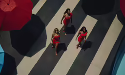 four women in red bathing suits walk along a street