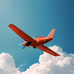 a small orange airplane flying through the air