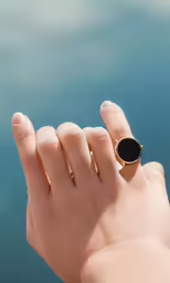 the person holds up their finger with a large stone ring on it