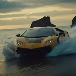 an orange sports car driving down a beach