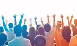 people standing with their arms raised up in front of the ocean