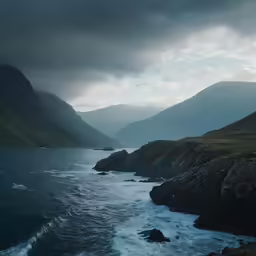 the view looking over the water towards mountains and waves