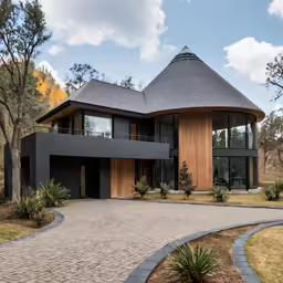 an unique house with a circular driveway surrounded by green trees