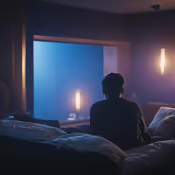 a woman sitting on the bed watching tv