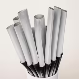 a small white vase holds six black and white plastic rods