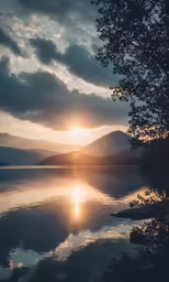 the sun shining on water with trees and mountain in background