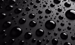 a lot of drops of black water on a black surface
