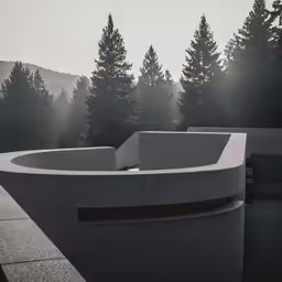 a curved concrete building with trees in the background