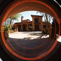 a photo looking through a circular window to a house