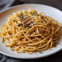 pasta on a white plate with chopped herbs and seasonings