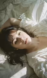 woman laying in bed with white sheet on her stomach