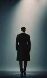 the man is wearing a coat and standing in front of a light