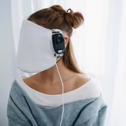 a woman is wearing a blindfold as she looks down and takes a picture