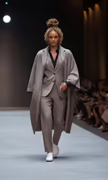 a person walking down the runway in an overcoat