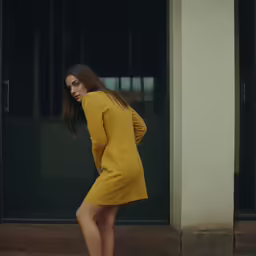 a beautiful young woman in a yellow dress standing outside