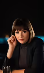 a beautiful woman sitting at a table with a glass of wine