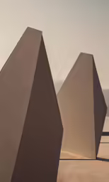 three geometric shapes stand upright in the middle of the desert
