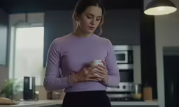 a young woman holding a coffee mug and looking at the camera