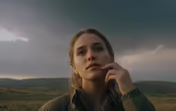 a woman with brown hair is staring at the sky