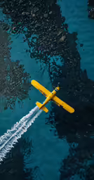 a small yellow airplane flying low over a body of water