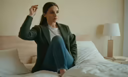 woman on a bed taking a selfie with her phone