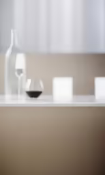 a bottle, glass and a salt shaker on a counter