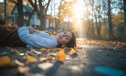 the young woman is laying in the leaves on the street