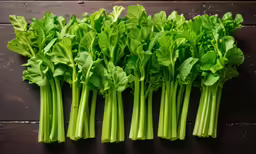a bunch of green stalks of leaves on a wooden surface