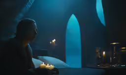 woman sitting at a table with candles in a dark room