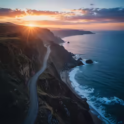 the sun is going down on an ocean coast and some mountains