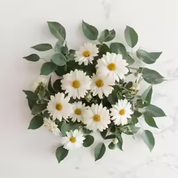 a bunch of flowers and some green leaves on a marble surface