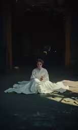 woman in white dress sitting on a floor by herself
