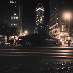 a night shot of a very tall building with cars on the street