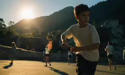 a group of boys run down the street in front of mountains