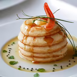 a stack of pancakes with tomatoes on top
