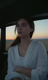 young woman in white shirt looking out the window