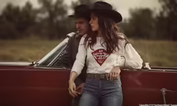 a young man standing next to a woman in a red convertible